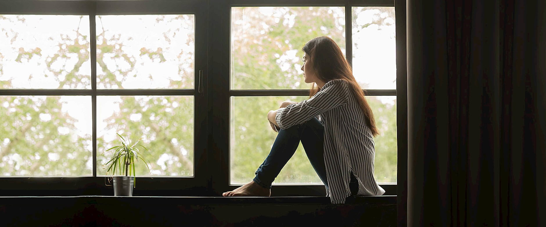 Woman sitting on the window sill looking out